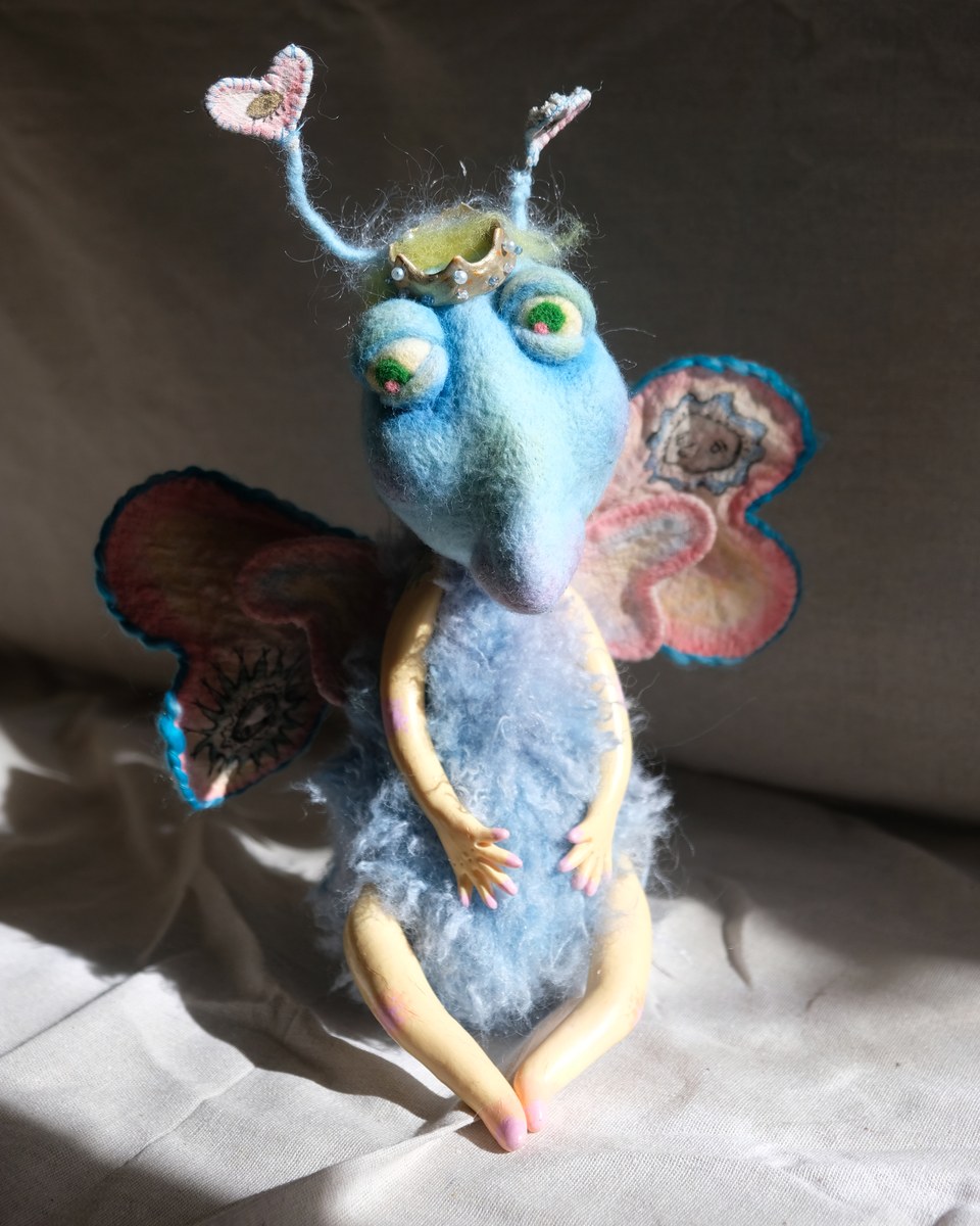 King Aster, a made-to-order blue handmade art doll with a crown, heart antennae, and soft wings.