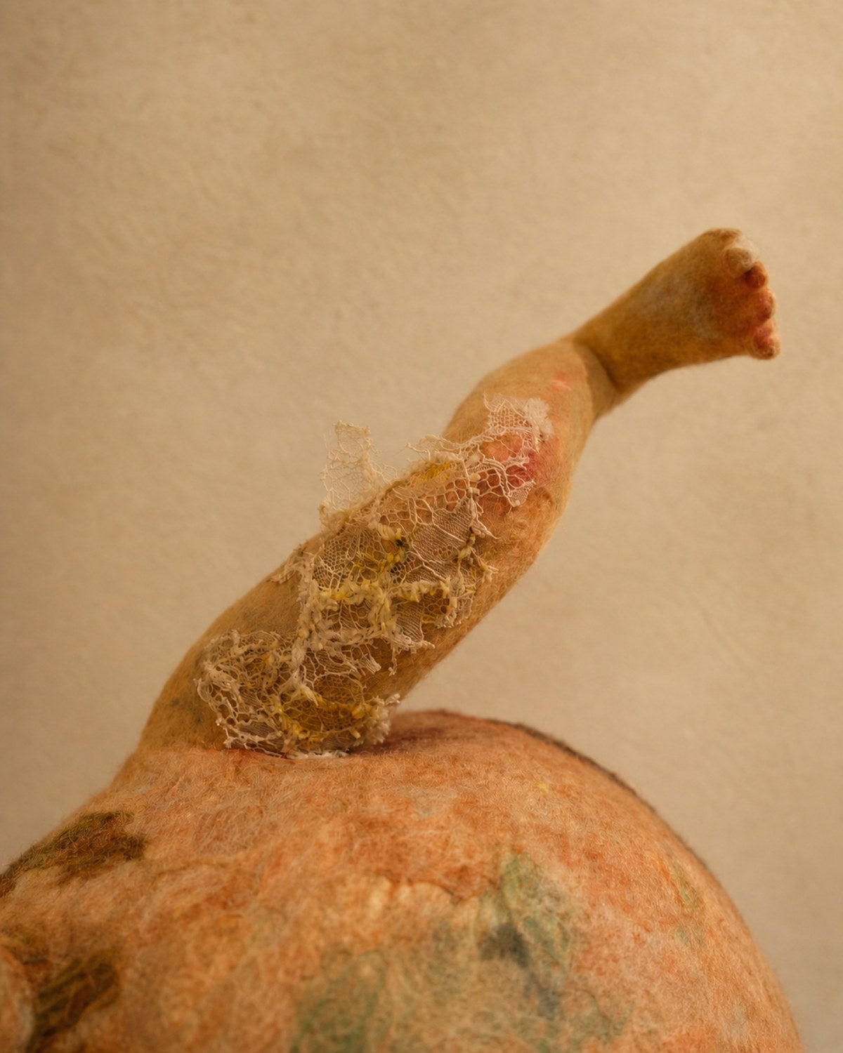 Leg detail of Broken Jar showing curved wool limbs, worn color, and delicate textile damage.