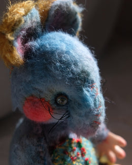 Close detail of Dream Thief's face, whiskers, rosy cheeks, and hand-stitched features.