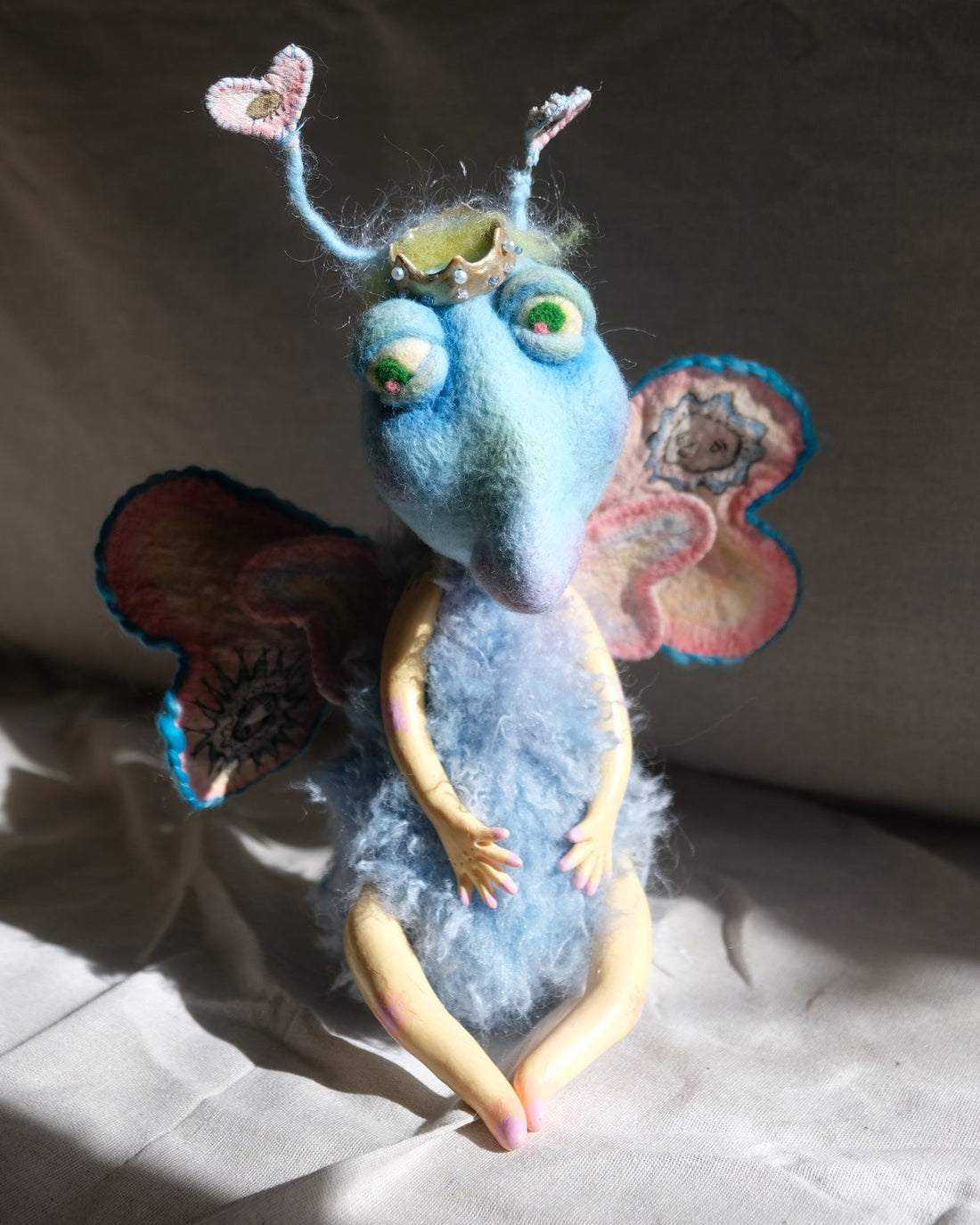 King Aster handmade art doll with heart antennae, crown, soft blue body, and stitched wings.