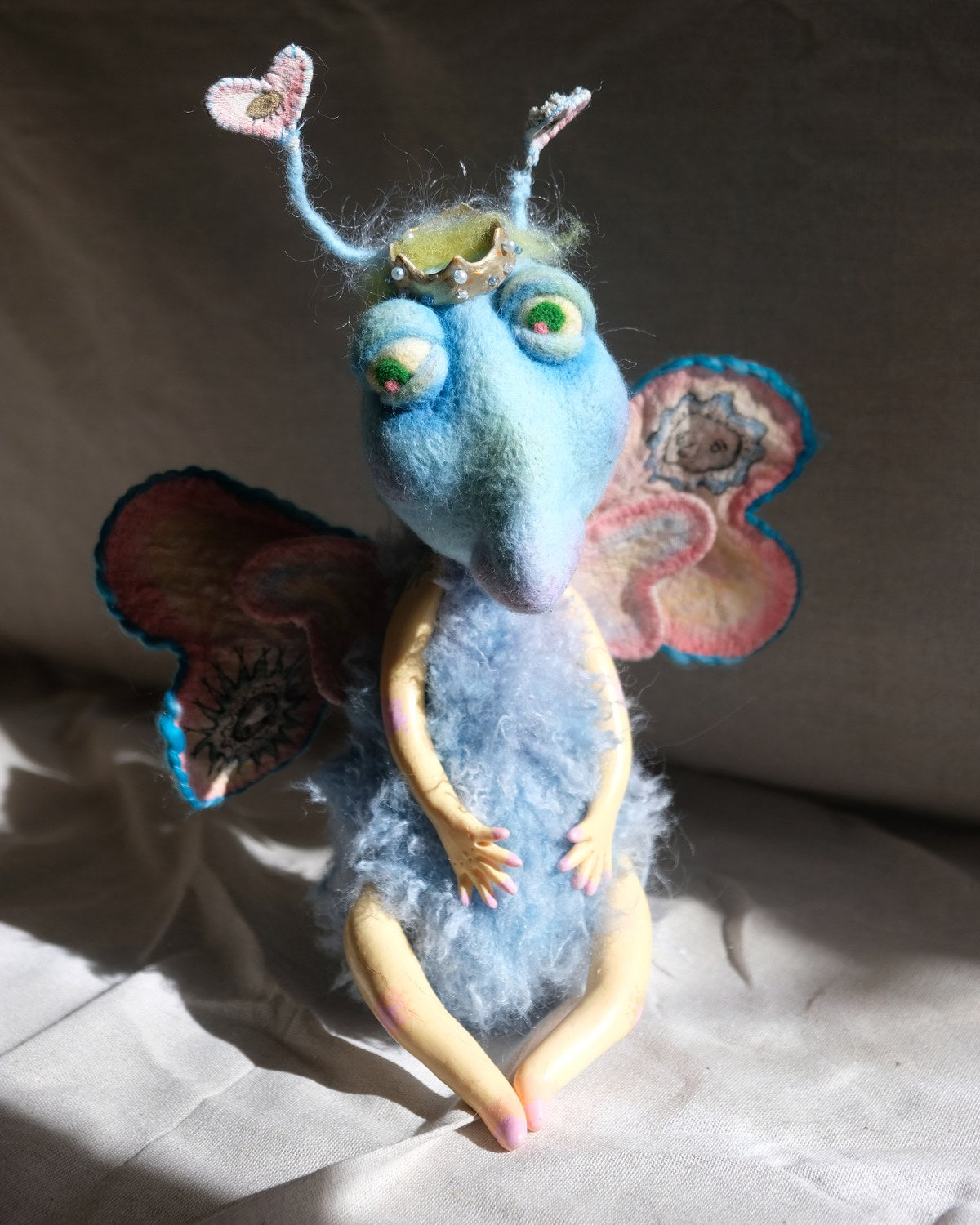 King Aster handmade art doll with heart antennae, crown, soft blue body, and stitched wings.