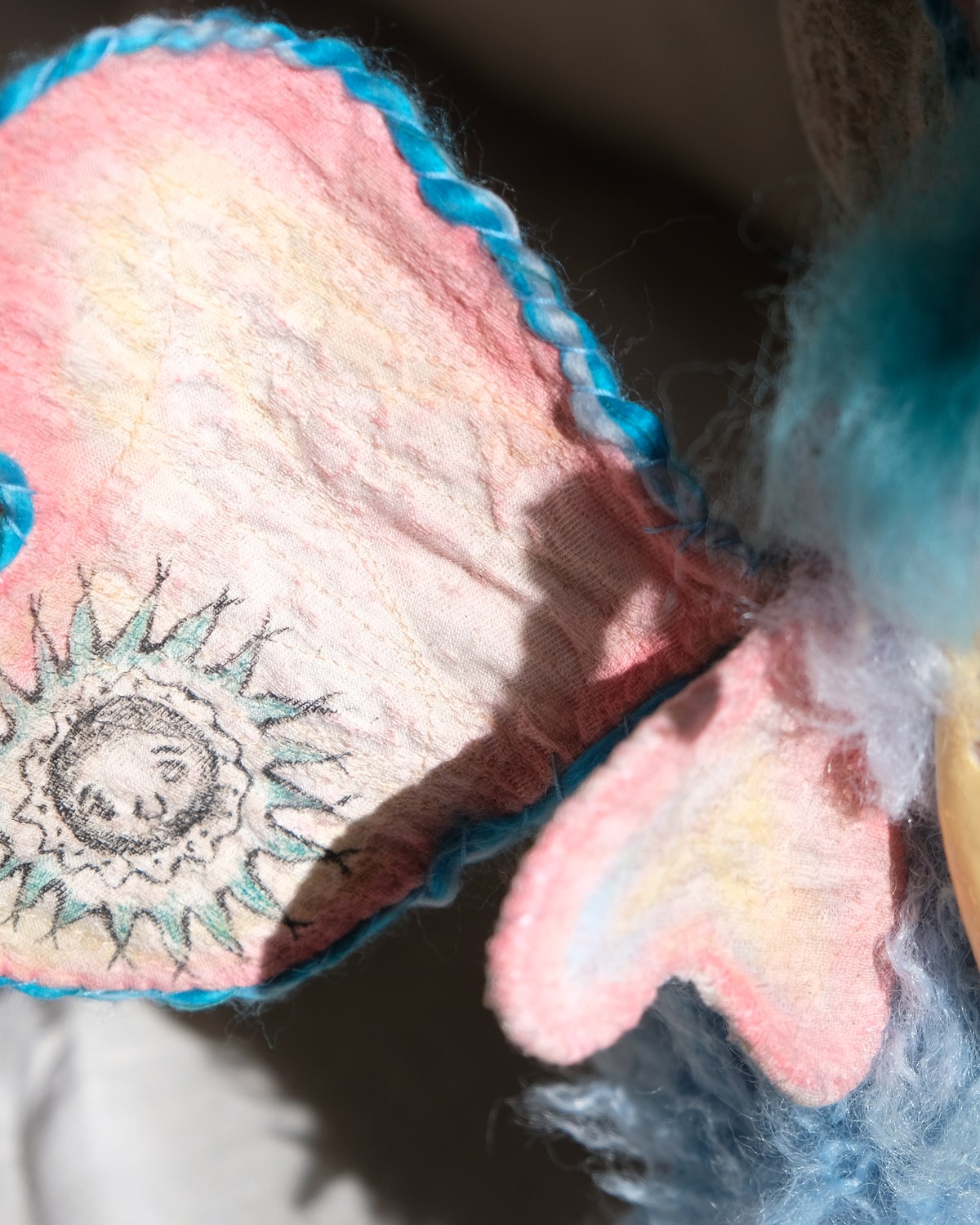 Left wing detail of King Aster showing soft pink textile color and handmade stitching.