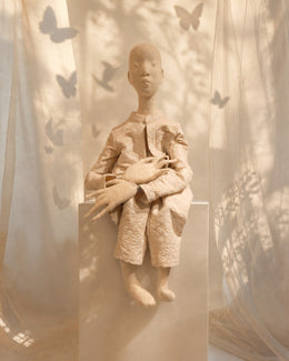 Full view of Zhuang Sheng - The Butterfly Dreamer, a large wool marionette soft sculpture seated among translucent fabric and butterfly shadows.