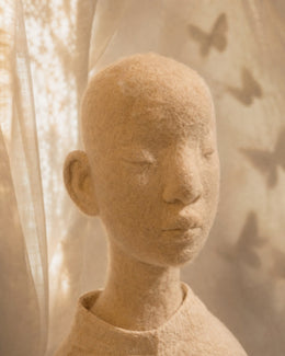 Portrait detail of Zhuang Sheng showing the hand-felted wool face, closed eyes, and soft butterfly-shadow atmosphere.