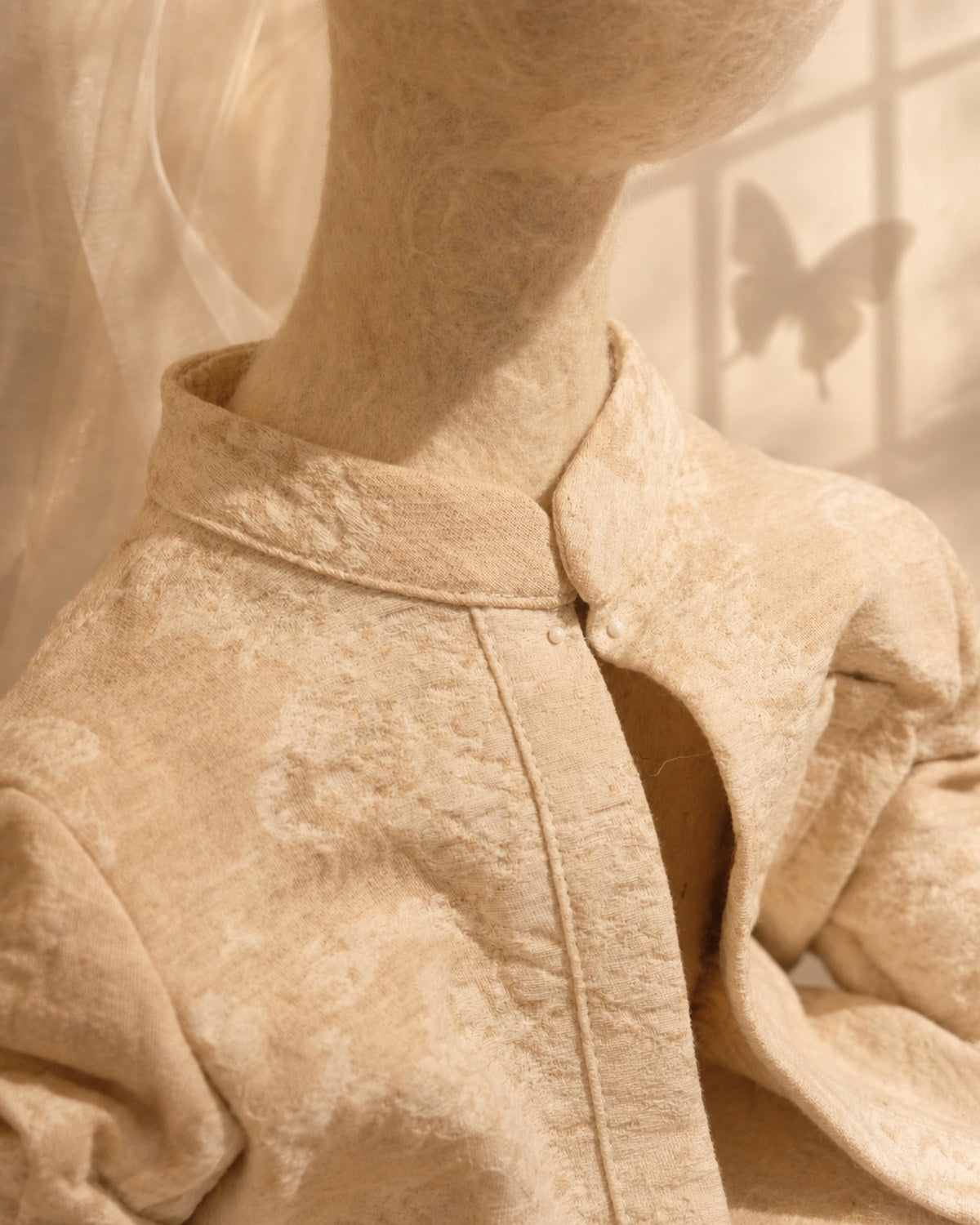 Clothing detail of Zhuang Sheng showing textured cotton textile, soft wool surface, collar, and small handmade fastenings.