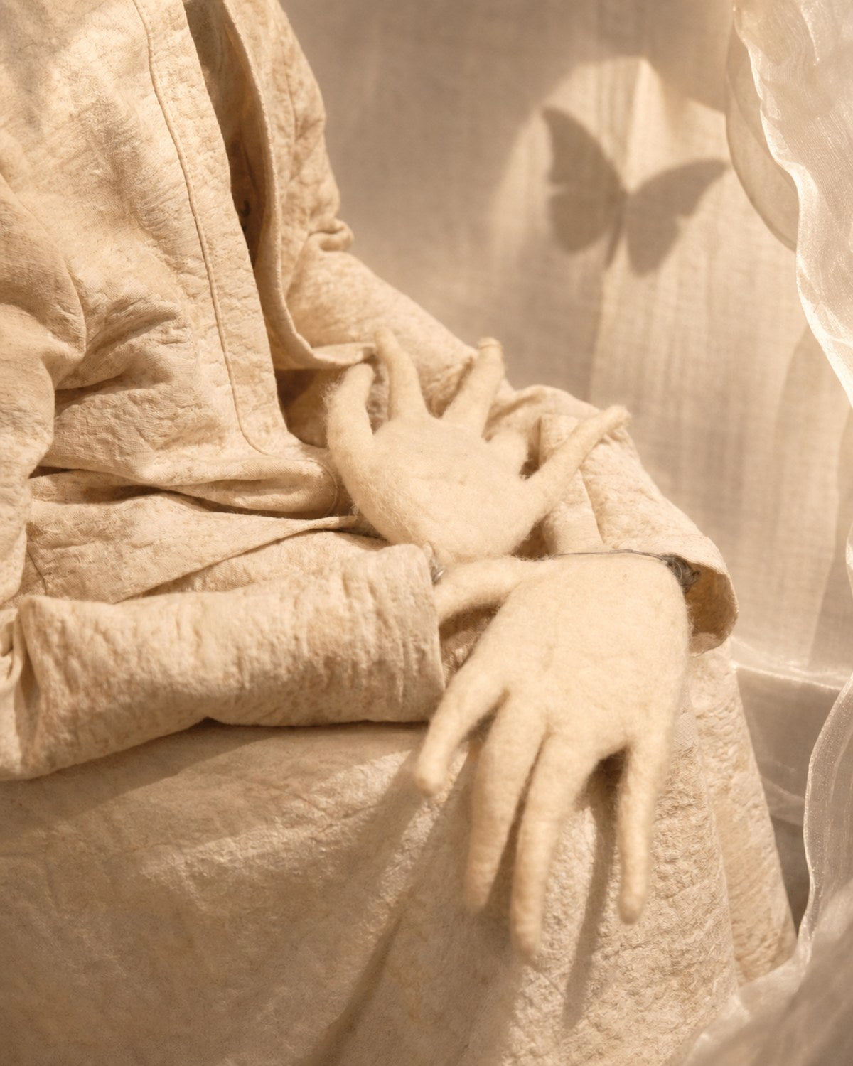Hand detail of Zhuang Sheng showing long wool fingers, textile folds, and the delicate marionette-like posture.